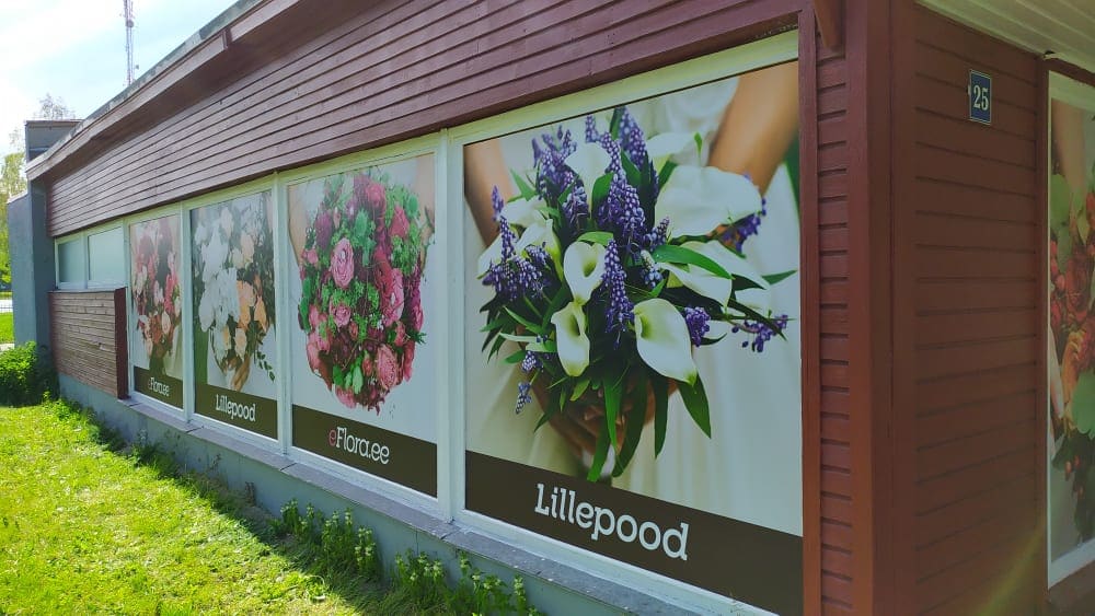 Decordsi portfoolio töö: lillefotod ja poe tähistus pikal, mitmeks klaasipinnaks jaotatud fassaadil.